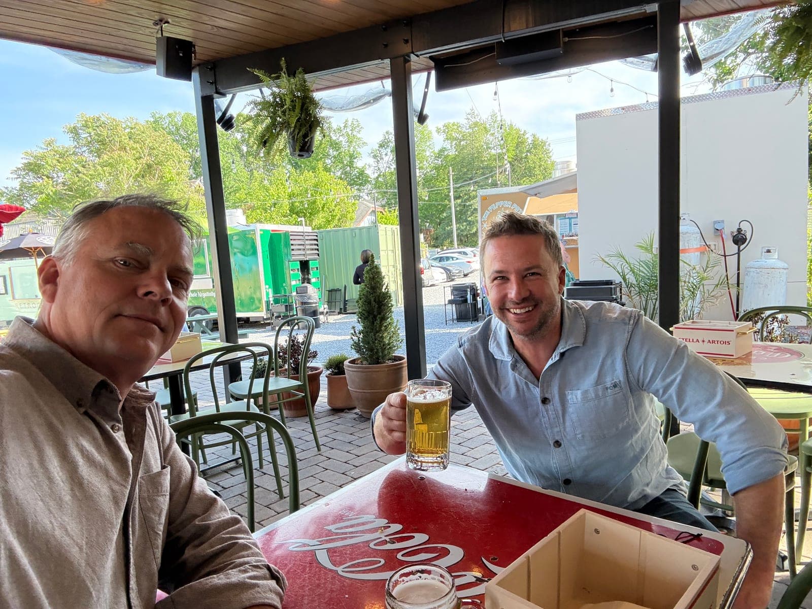 Selfie of Trey Stephenson and Craig Hawkins sharing beers on the patio at Lost and Found in Nashville, Craig raising his glass toward the camera.